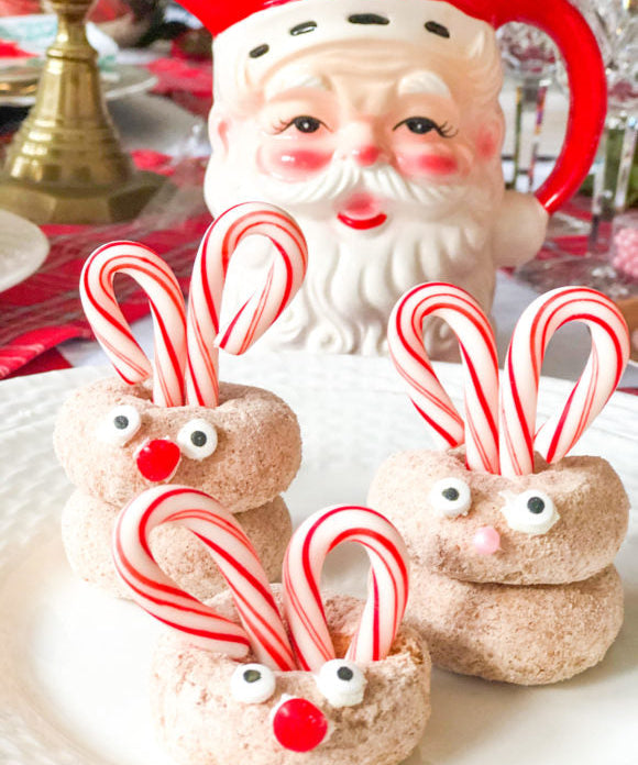 mini rudolph doughnuts with candy cane antlers and candy eyes and nose with santa pitcher in background