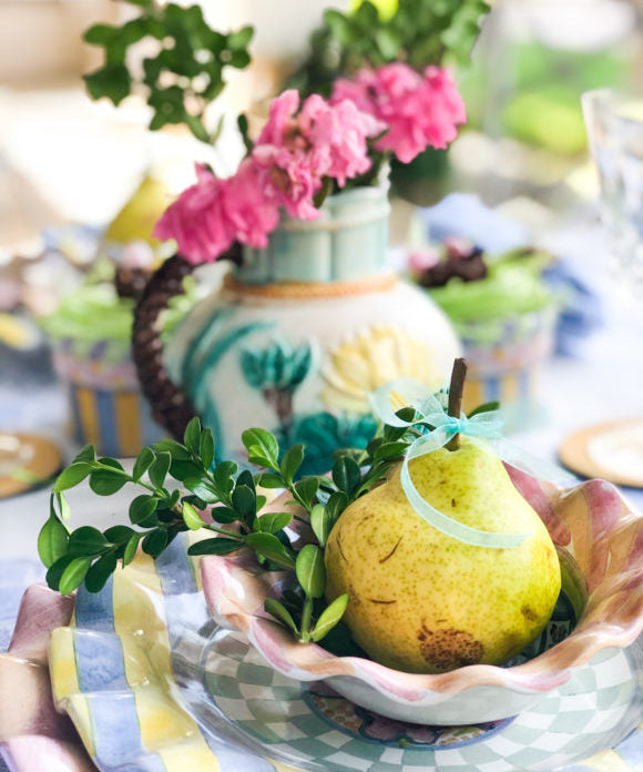 stack of plates with pear in top bowl with boxwood clippings
