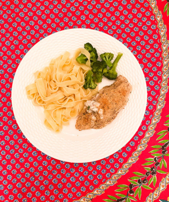 chicken with cream cheese broccoli and egg noodles on white plate and red floral tablecloth