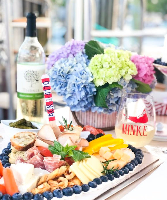 charcuterie board with cheese meat and fruit on boat with wine and flowers