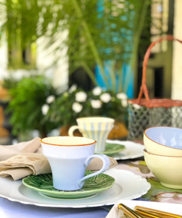 table set with white green lavender on porch with plants and a blue door