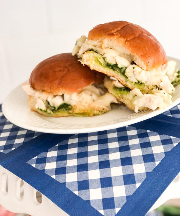 chicken pesto sliders with cheese on white plate and blue gingham napkin