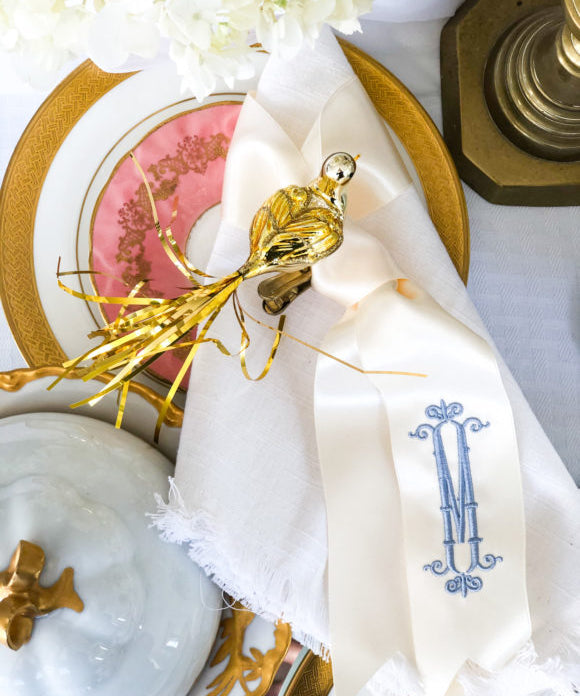 stack of plates with white napkin with ribbon and metallic bird ornament