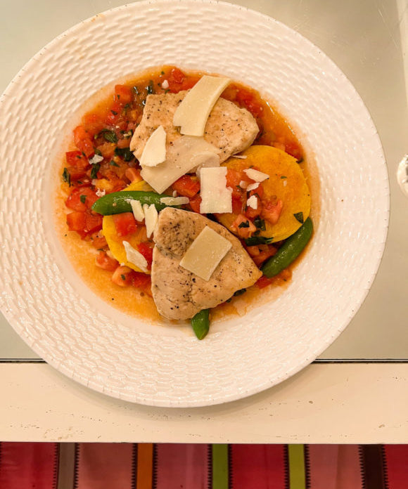 roasted chicken with polenta cakes and tomato sauce on white plate on table with mirrored top
