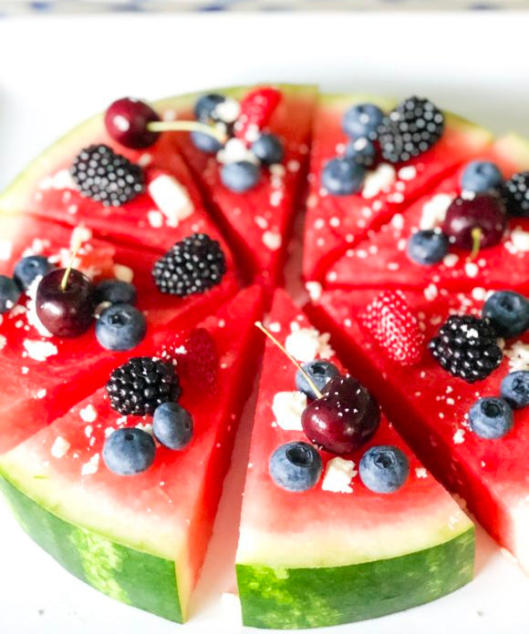 watermelon pizza sliced in a circle and cut into triangles topped with berries and feta cheese