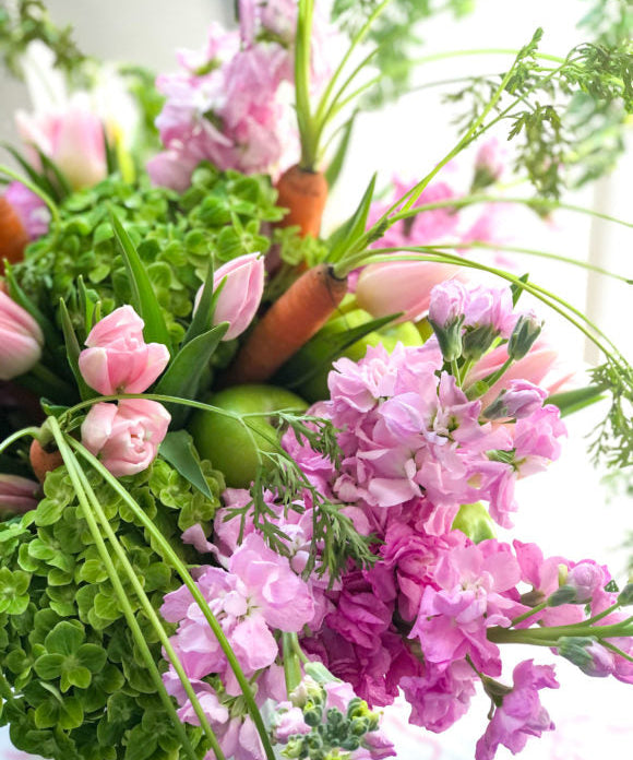 easter flower arrangement in pink and green with orange carrots with stems