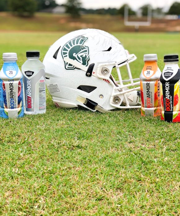 football helmet in grass with 2 bodyarmor bottles on each side