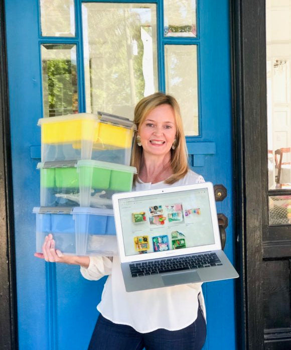 lady in front of blue door with computer and boxes introducing her square online store