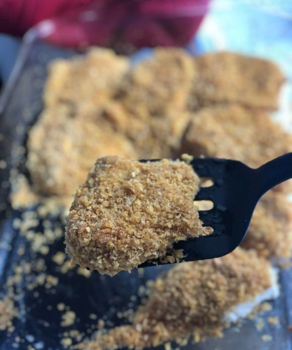 cornflake friend chicken on black spatula in clear dish