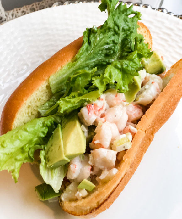 shrimp roll with green lettuce and avocado slices on brioche bread