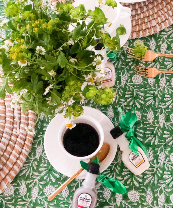 green tablecloth with coffee in white cup and saucer and green plant