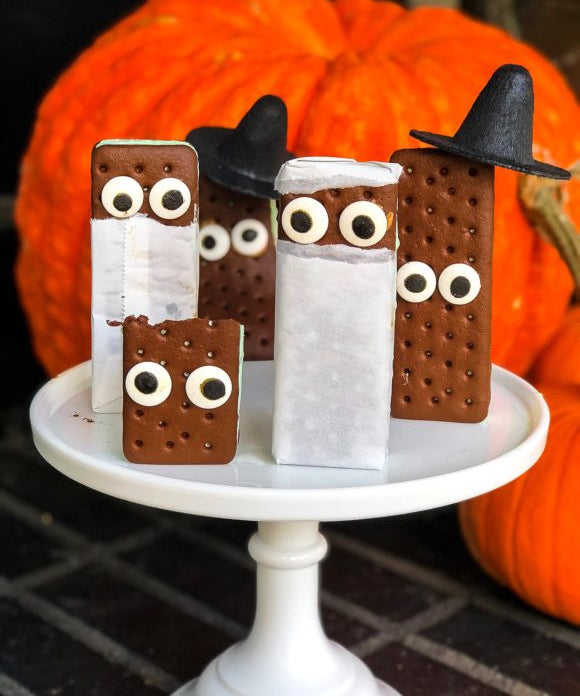ice cream sandwiches dressed up for halloween with candy eyes and witch hats