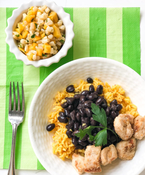 chicken with yellow rice and black beans with mango salsa on the side in a bowl