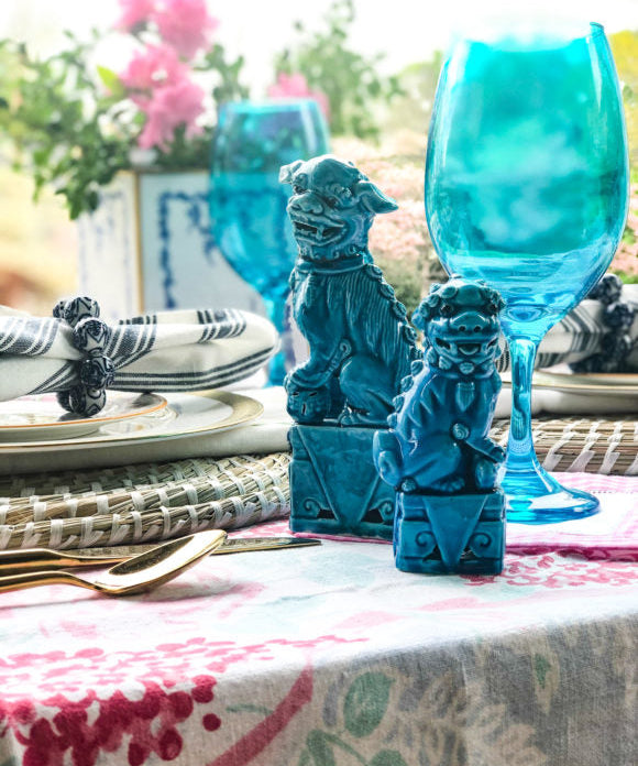 outdoor table set with plates and decorated with turquoise foo dogs