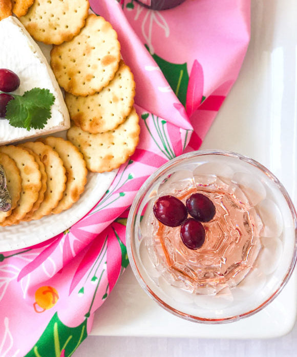 pink poinsettia cocktail with pink and green napkin crackers and cheese