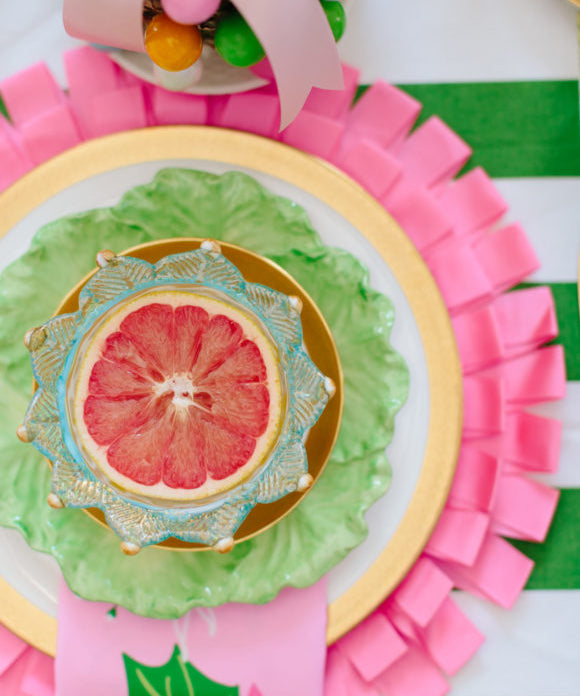 pink and green place setting with half of a grapefruit
