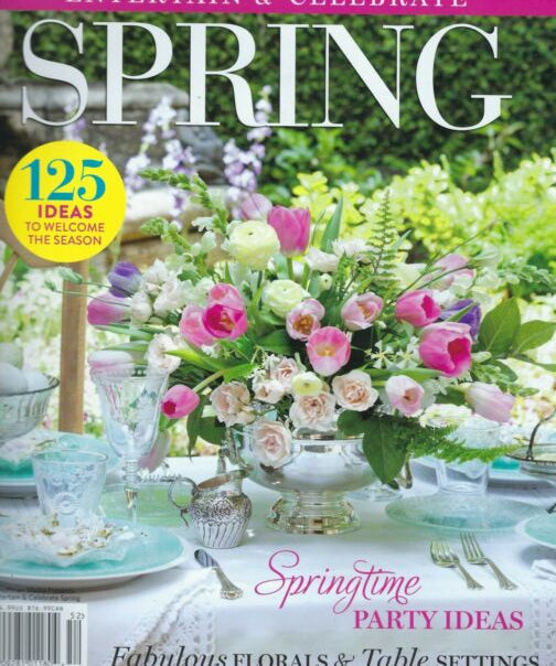 spring magazine cover with table set in white pink and blue with bright pink green and white flower centerpiece
