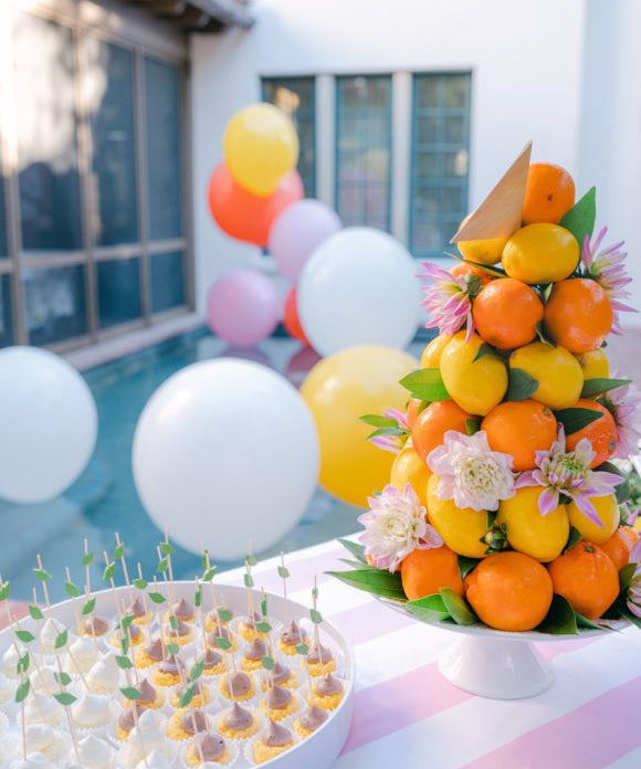 citrus party by the pool with cake bites and balloons