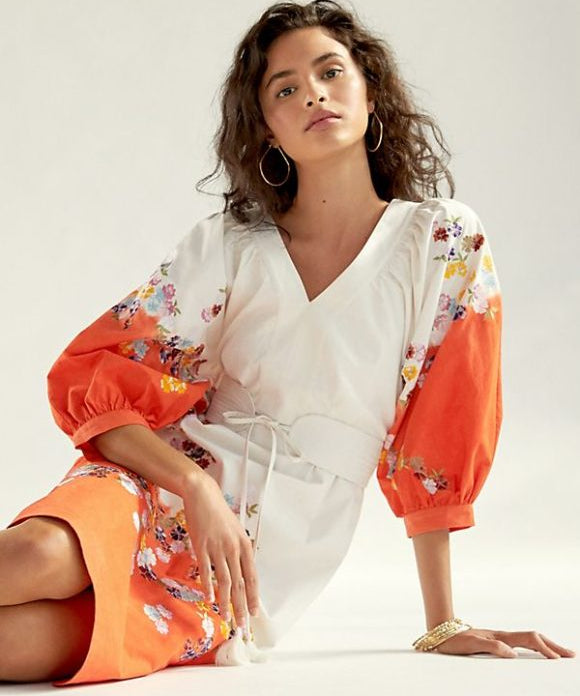 brunette lady in white dress with orange sleeves and embroidered flowers