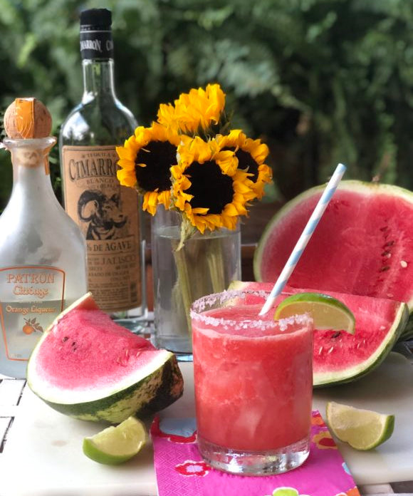watermelon margarita in glass with lime garnish and sunflowers