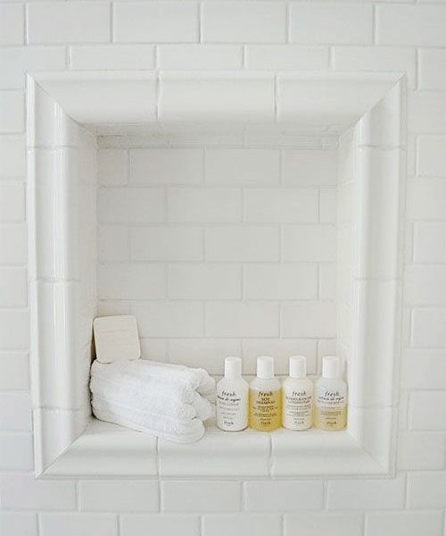 white subway tiles in show nook with shampoo soap and wash cloth