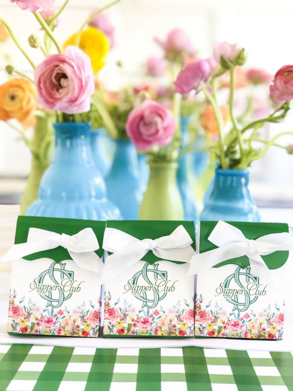 table set with green and white gingham placemats flowers in blue vases and favor boxes