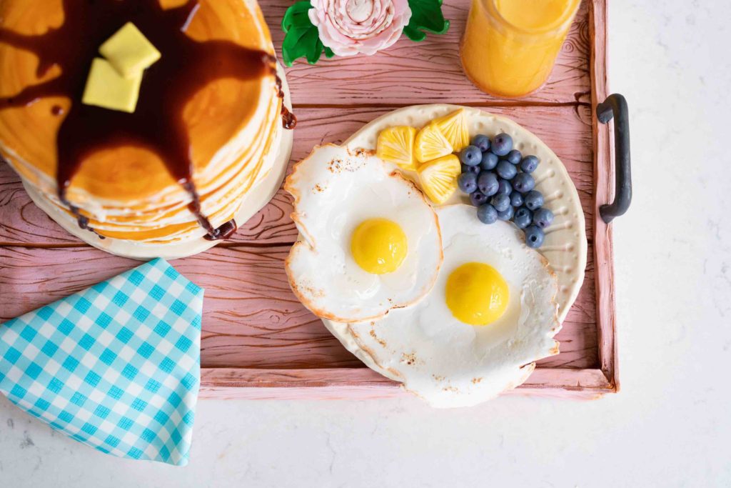 birthday cake that looks like breakfast served on a tray with eggs fruit and pancakes