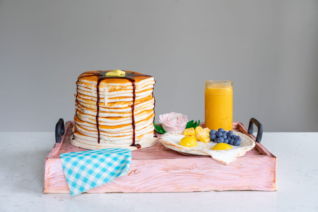 birthday cake shaped like breakfast on a tray with pancakes eggs fruit and juice