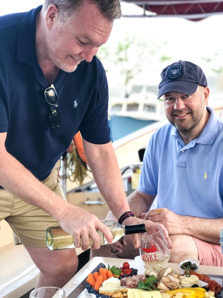 two men on a boat one pouring wine into a glass