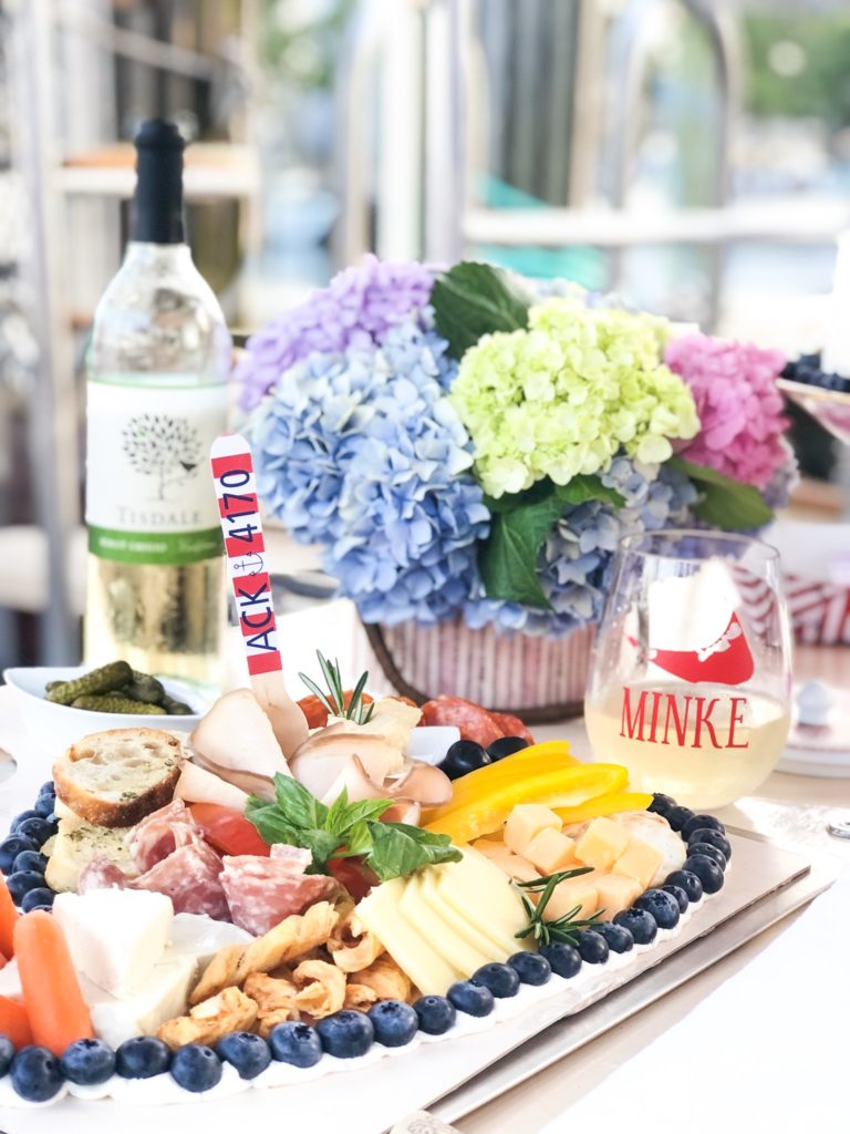 charcuterie board with cheese meat and fruit on boat with wine and flowers