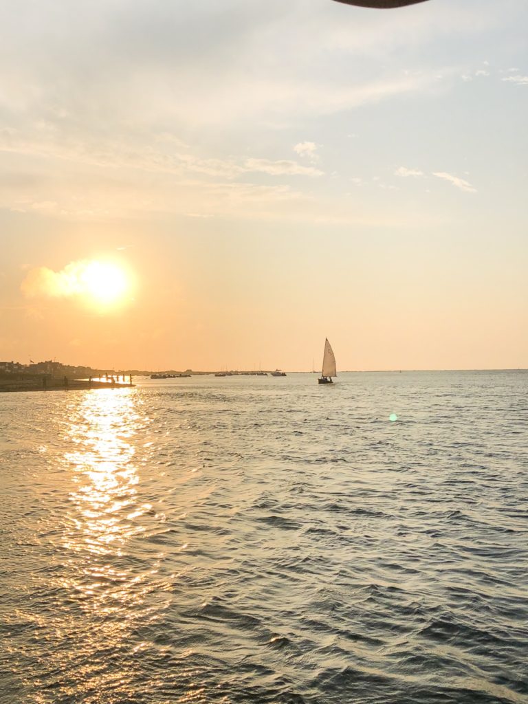 sunset in nantucket harbor with sailboat in photo