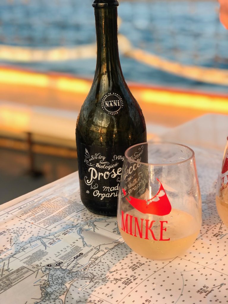 a black bottle of prosecco with a monogrammed wine glass on a sunset cruise aboard the Minke
