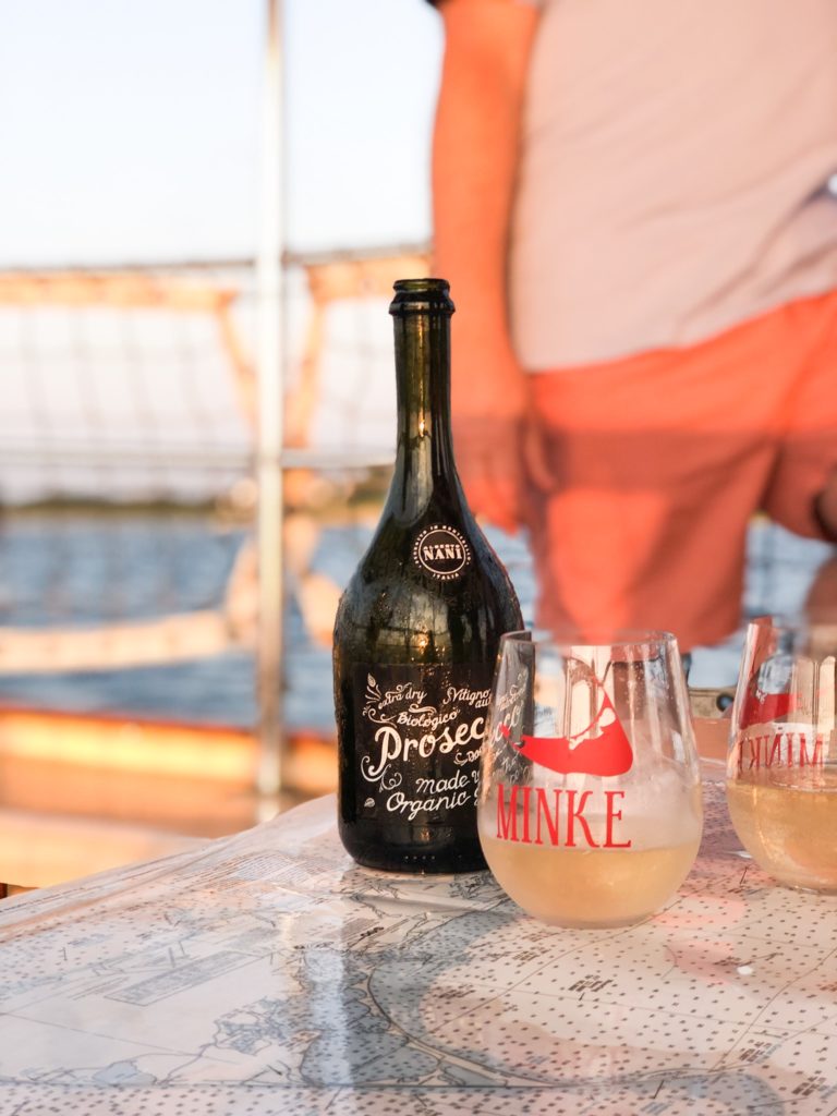 Bottle of Prosecco with acrylic wine glass in front of man with Nantucket Reds