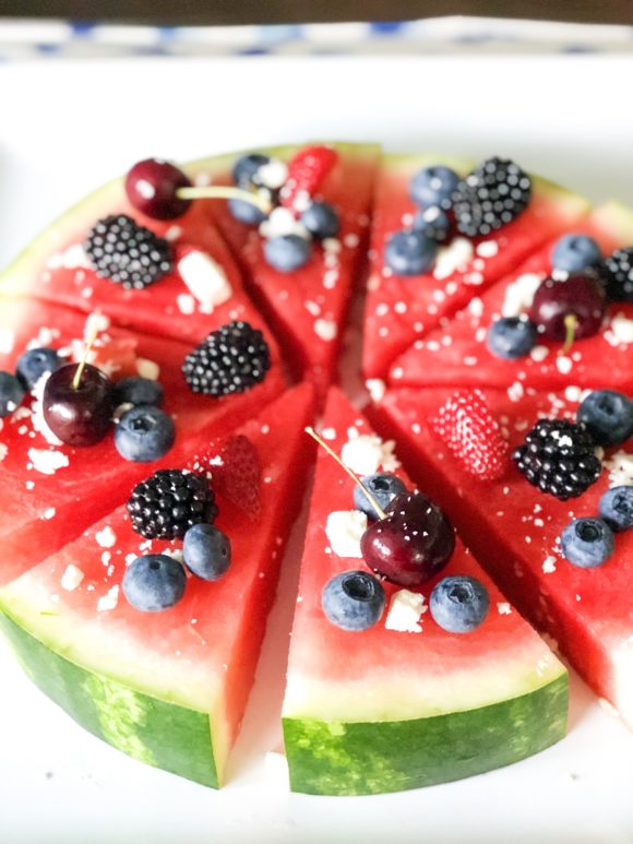 watermelon pizza sliced in a circle and cut into triangles topped with berries and feta cheese