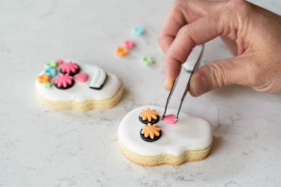 cookie decorator adding nost to skull cookie for day of the dead
