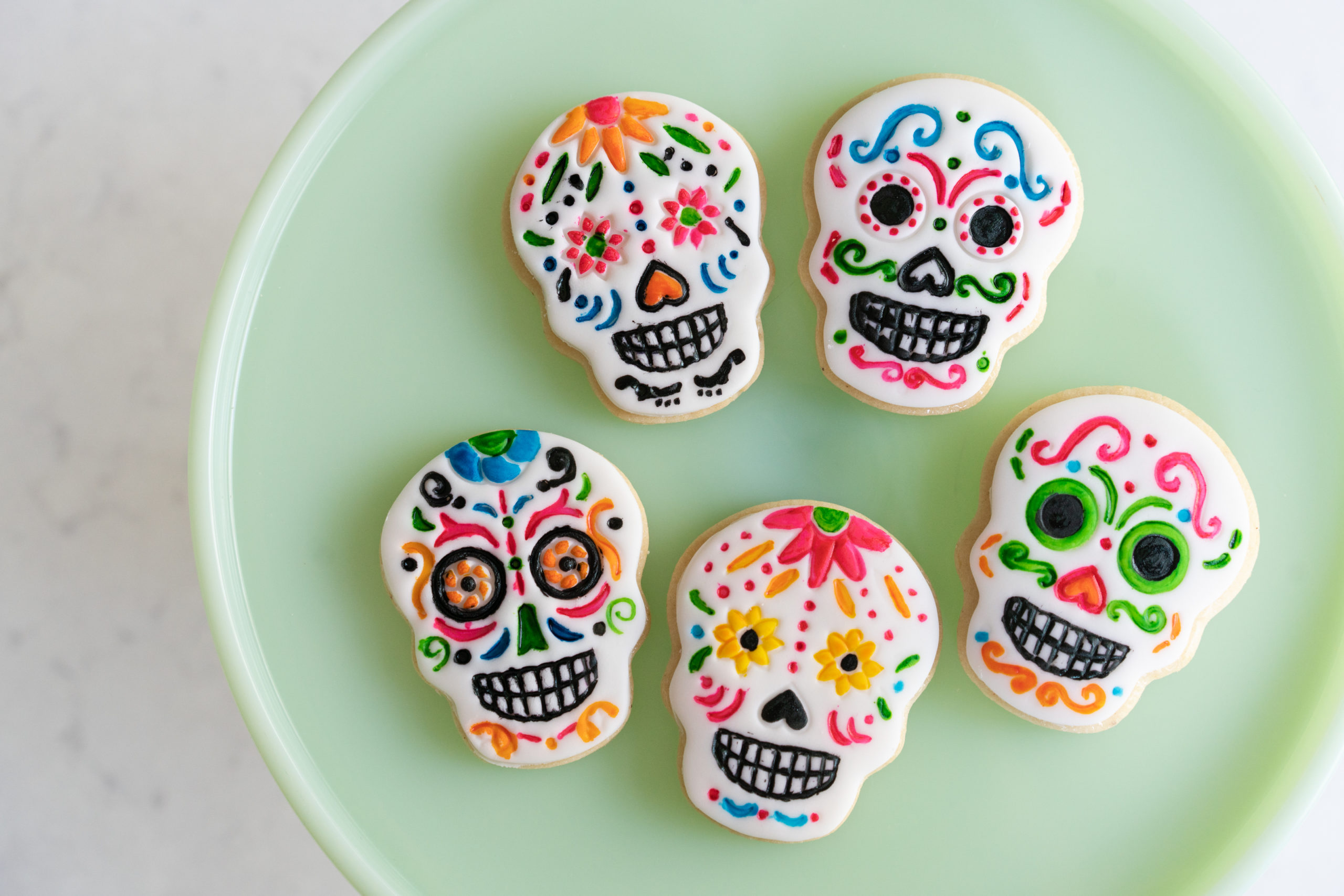 skull cookies with bright colors and flowers painted on them for day of the dead