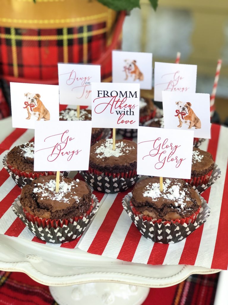 chocolate chip brownie muffins with powdered sugar on top and a football cupcake topper