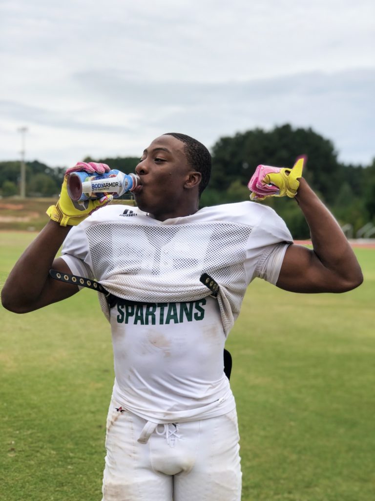 football player flexing muscle and drinking bodyarmor sports drink