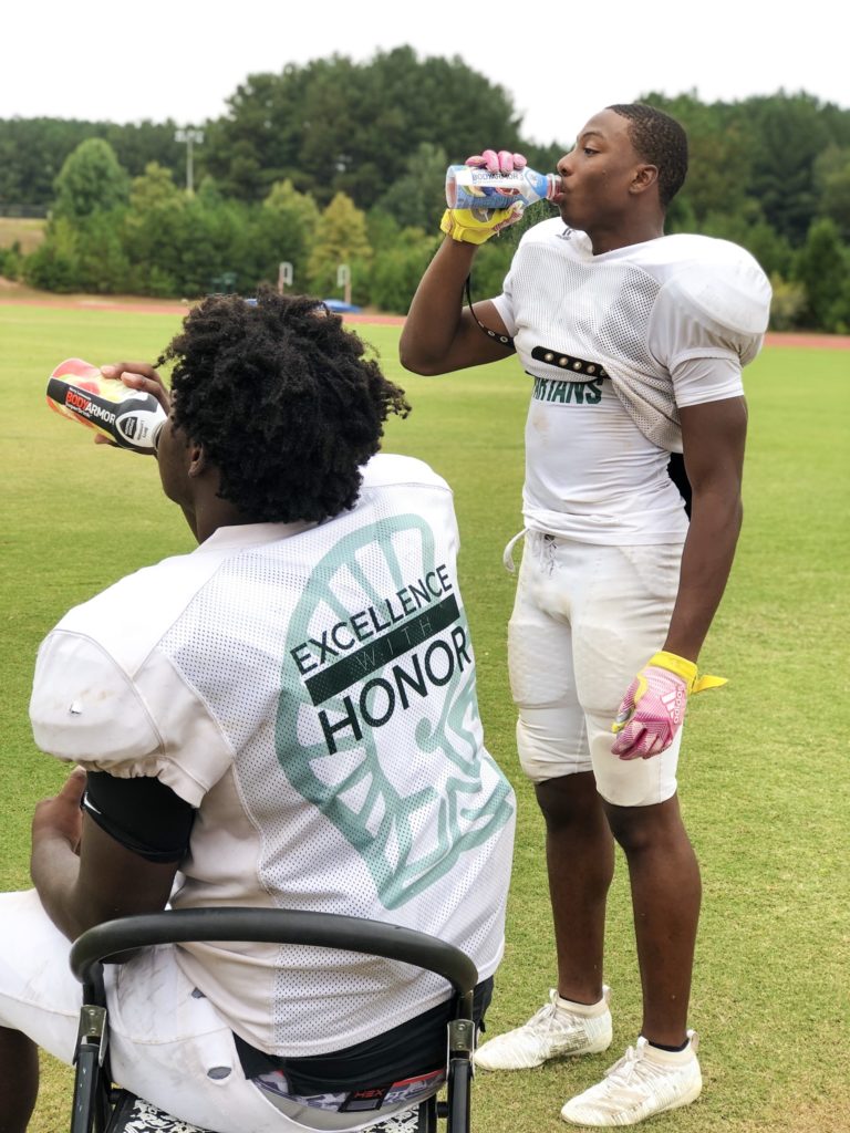two football players drinking bodyarmor sports drink