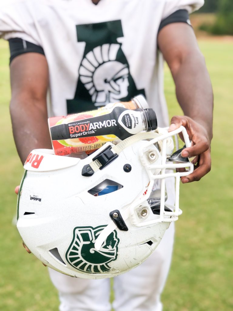 football player holding helmet full of BODYARMOR sports drinks