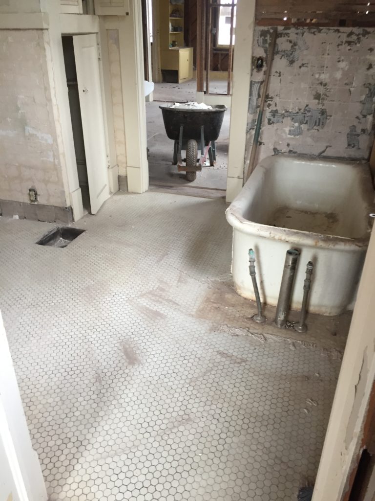 home remodel guest bathroom demolition phase dusty floor with tile on wall removed