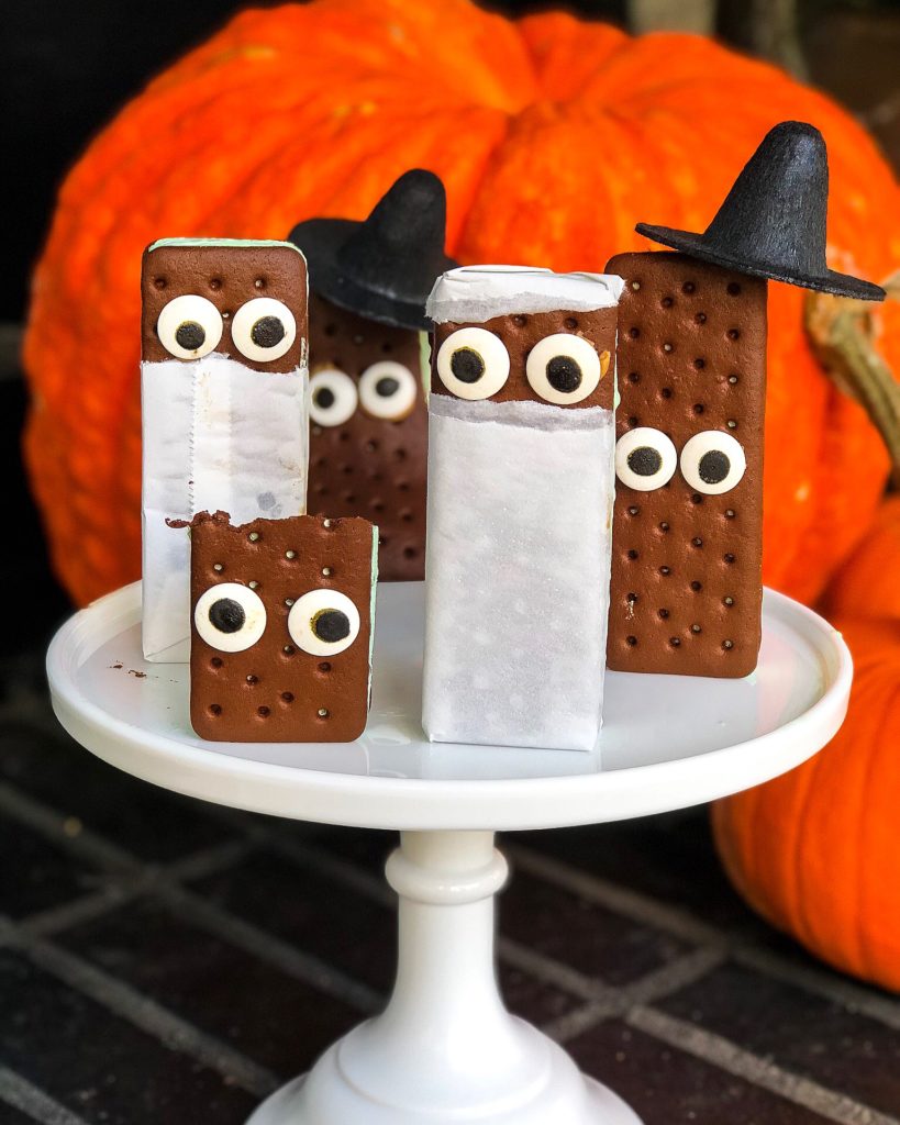 ice cream sandwiches dressed up for halloween with candy eyes and witch hats