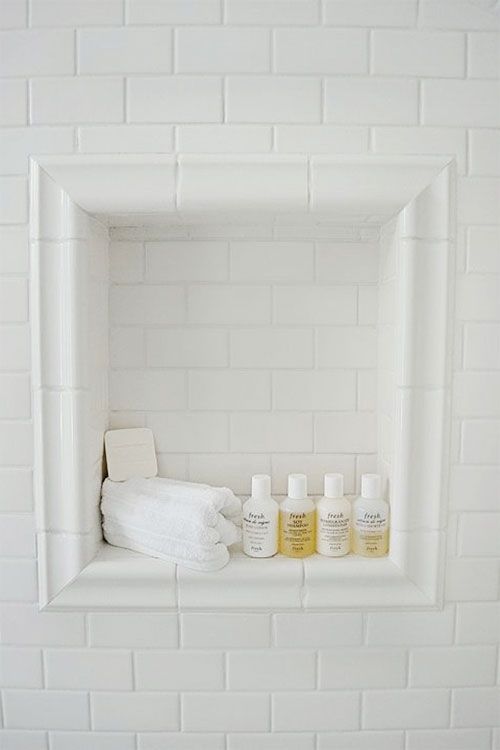 white subway tiles in show nook with shampoo soap and wash cloth