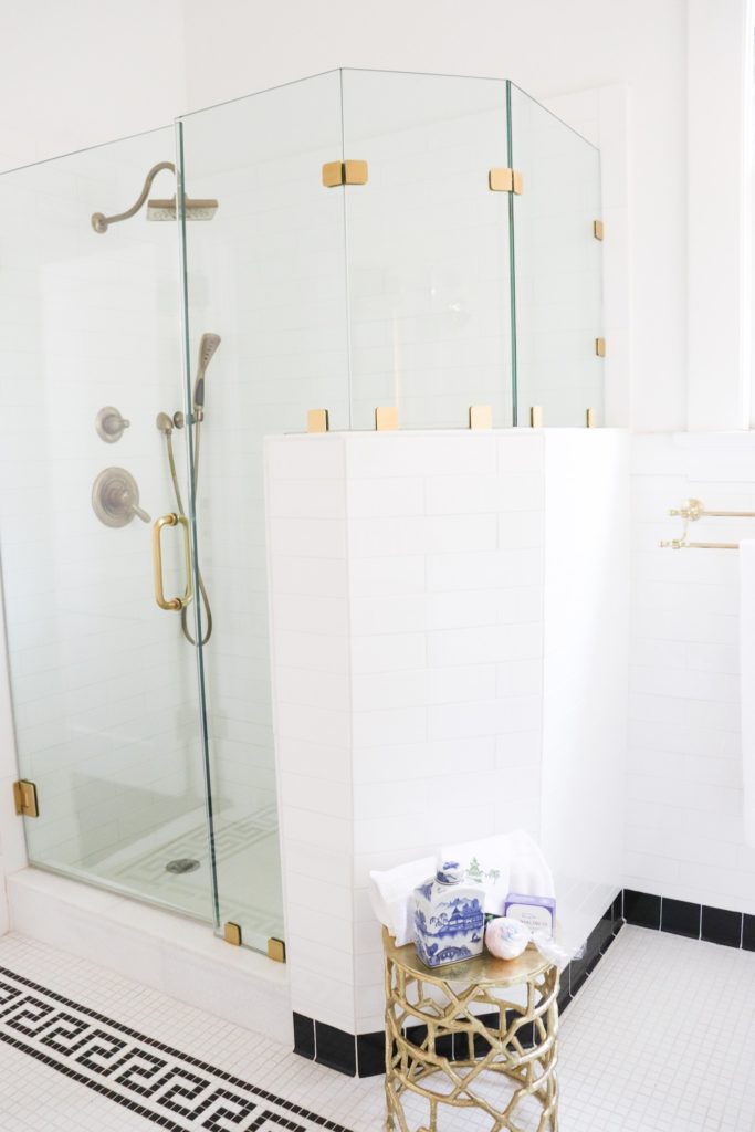 glass shower with white tile and brass hardware