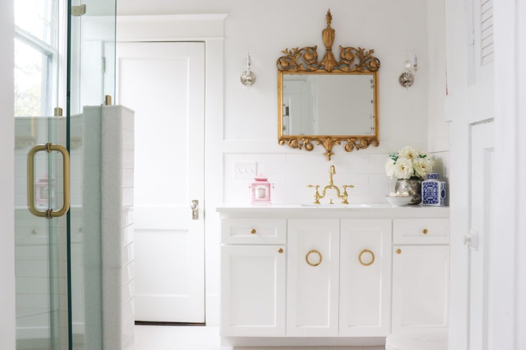 white bathroom with glass shower and antique brass mirror