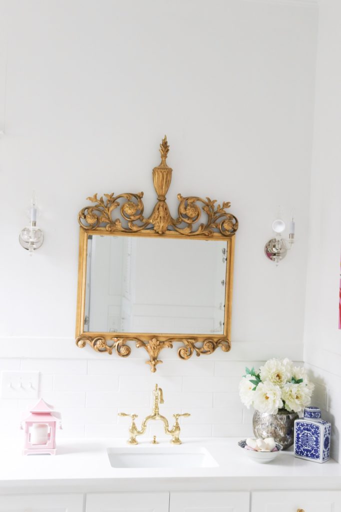 white bathroom with antique brass mirror over sink