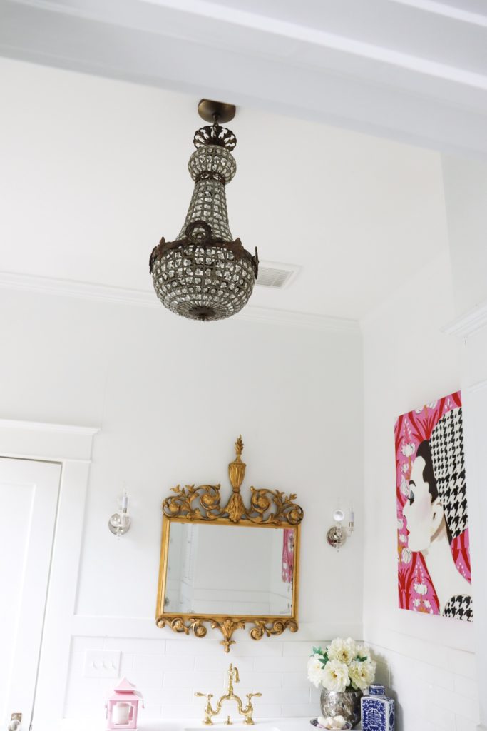 white bathroom with antique chandelier brass mirror ashley longshore painting