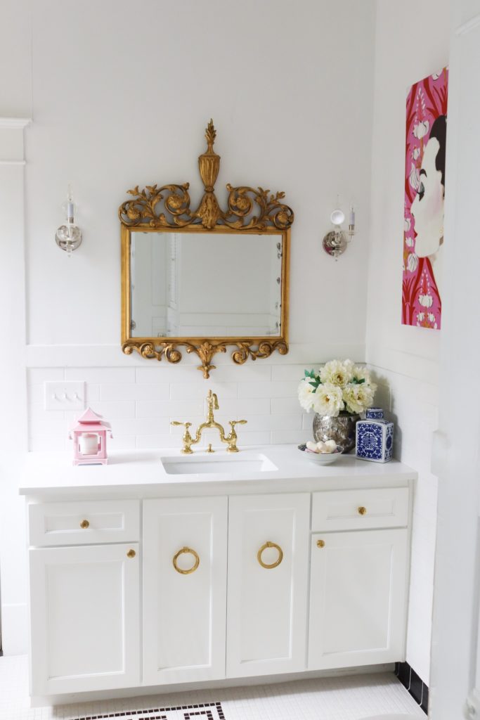 white bathroom with brass accessories and antique brass mirror