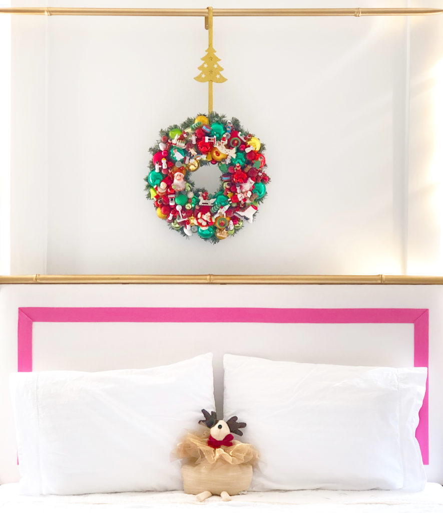 Christmas wreath with vintage ornaments hanging over bed