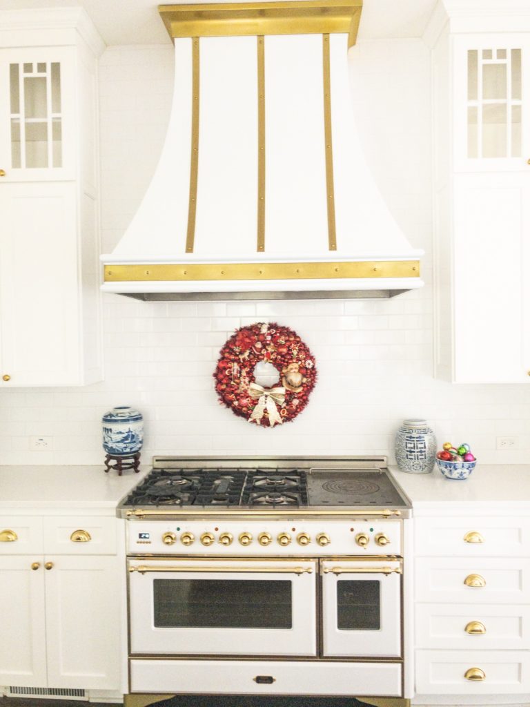 white and brass kitchen with red jewelry wreath